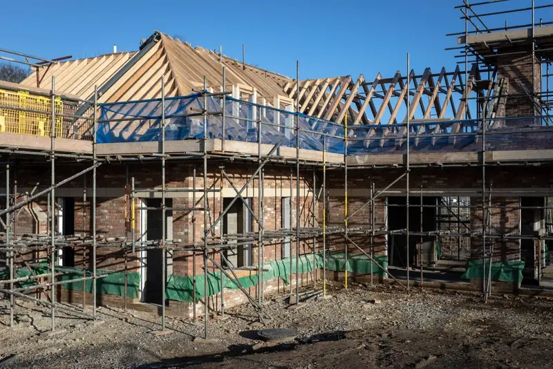 New home under construction with scaffolding and roof trusses