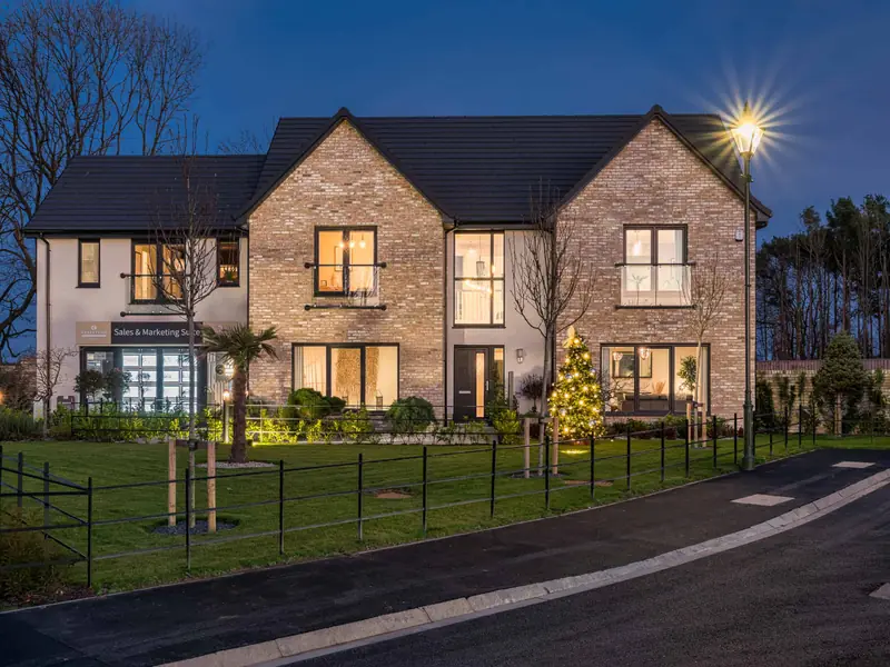 Brick detached house with black estate railings at dusk